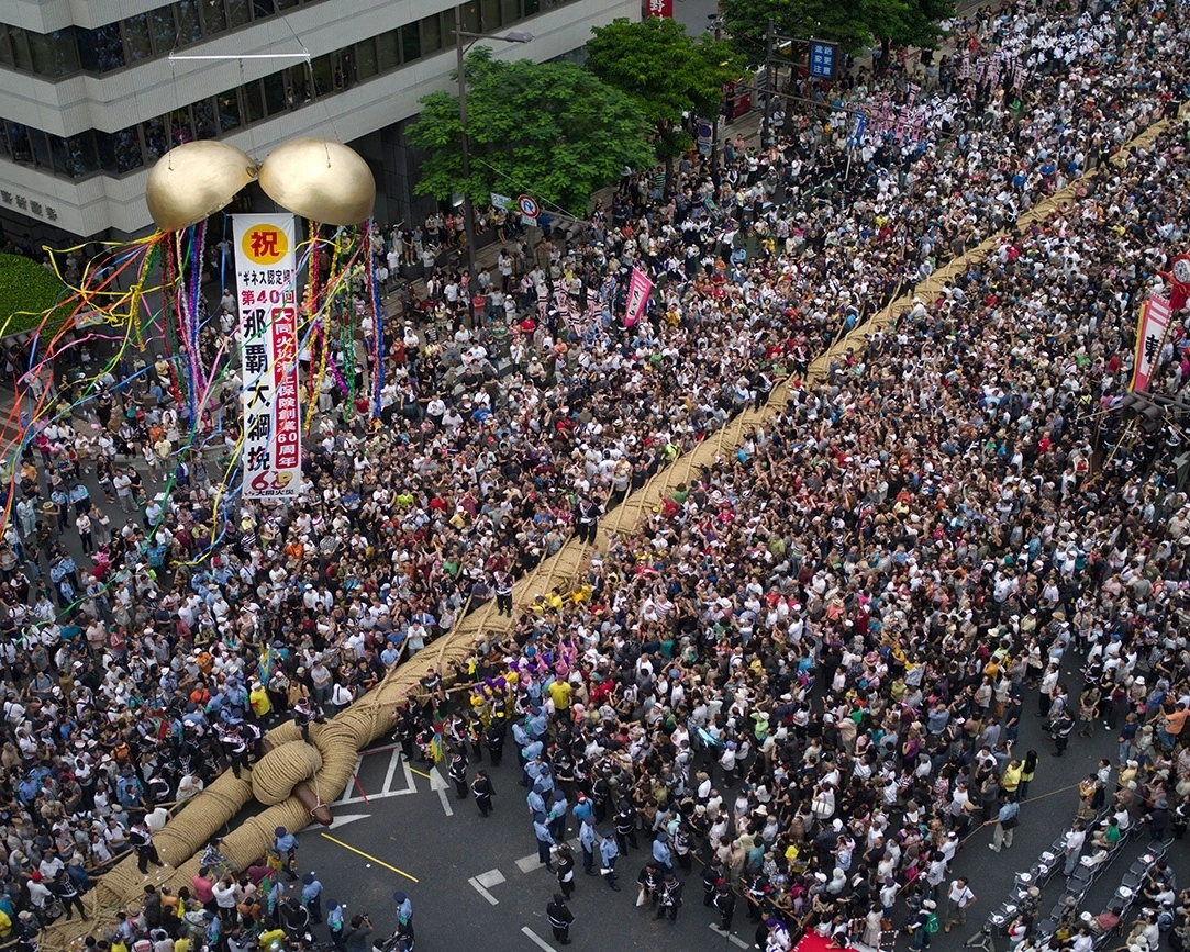 Naha Ōtsunahiki mit Flaggen und dichter Stadtmenge
