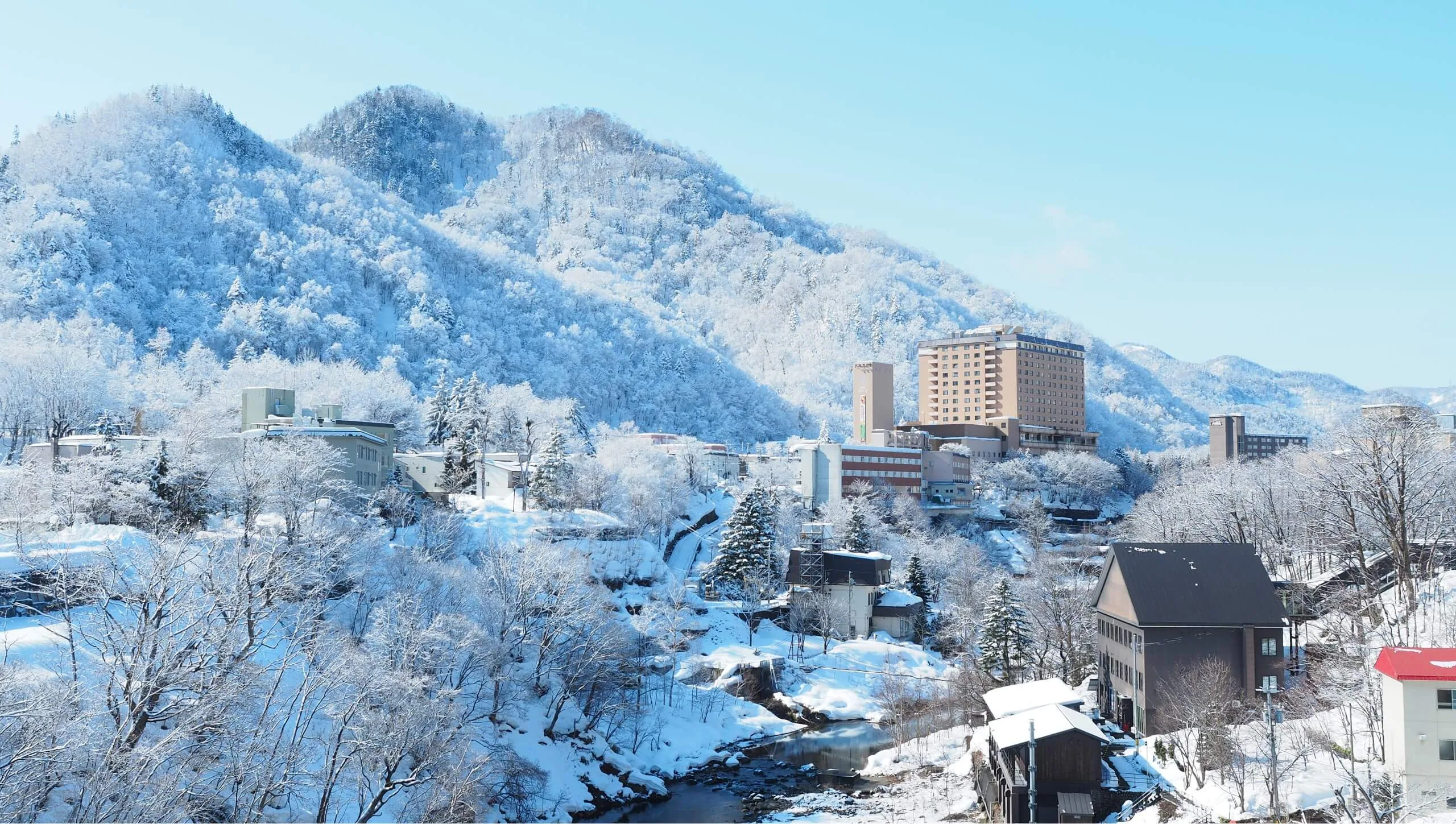 Jozankei Onsen im Winter mit verschneiter Straße und Bergen